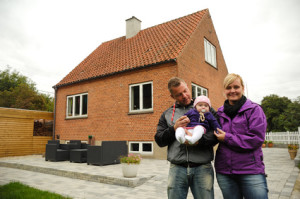 Family hugging in front of house