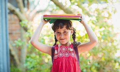 Girl carrying binders on her head.