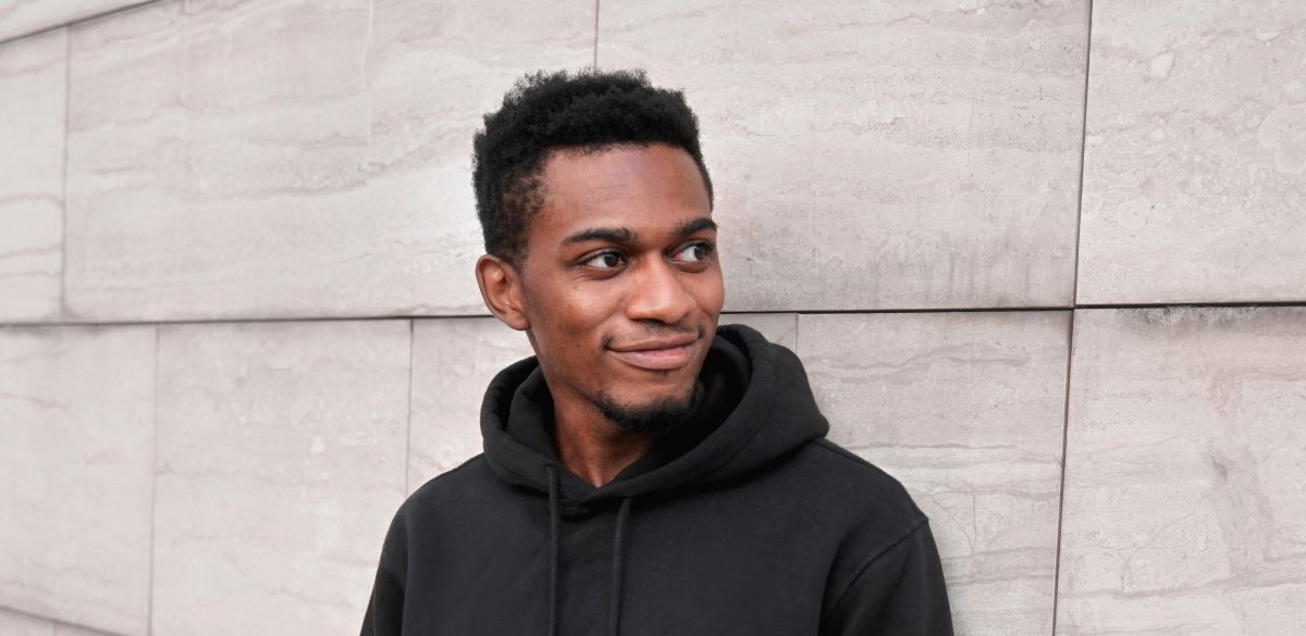 Head shot of a young man against a stone building