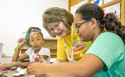 Woman helping children with crafts.