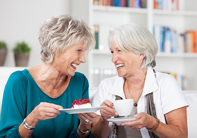 Two women laughing, eating cheesecake