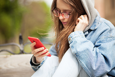 Girl with red cellphone outside