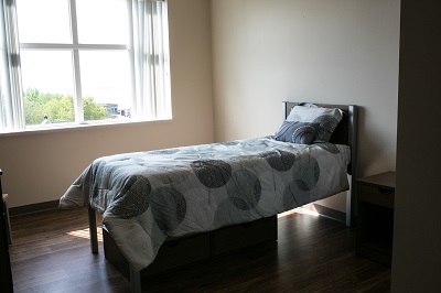 Bed next to a large window at Renaissance Transitional Housing