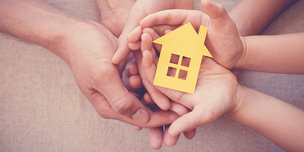 Hands holding a yellow paper house