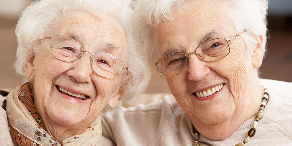 Two women hugging and smiling and looking at the camera