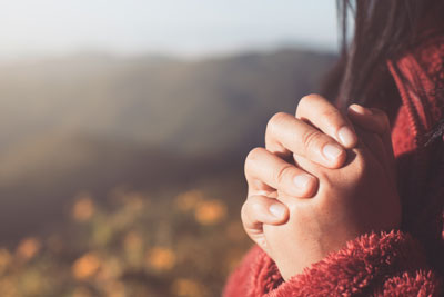 Girl with prayer hands outside