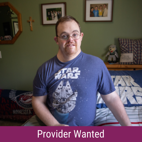 A man with Down syndrome sitting on a bed, wearing a Star Wars t-shirt and smiling, with the text "Provider Wanted"