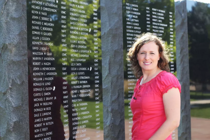 Jolaina standing in front of a memorial wall.