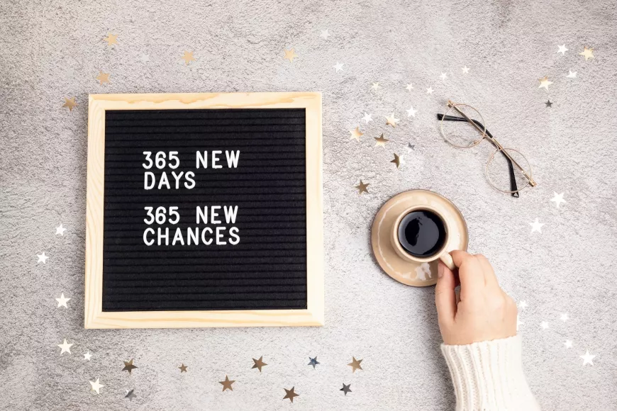 Glasses and coffee cup on a table. Message on a board: 365 New Days. 365 New Chances.