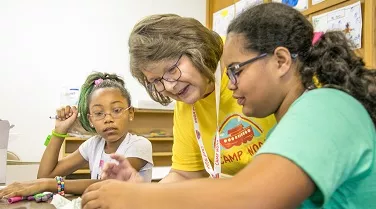 Woman helping children with crafts.