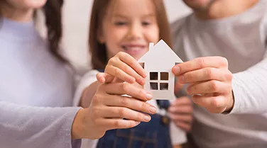 A family holding up a paper house cutout together